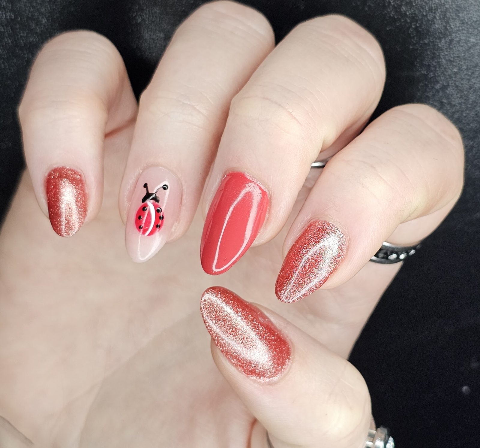 Rode cat eye-nagels met een lieveheersbeestje als nail art