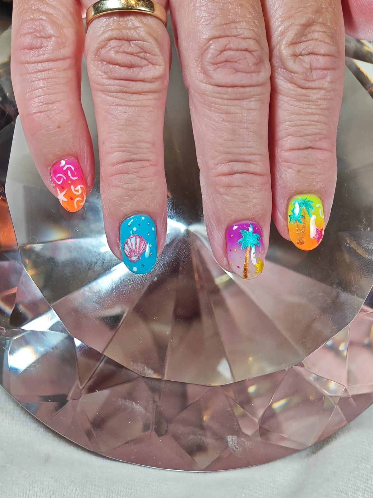 Zomerse nail art in felle kleuren, handen op een geslepen kristal
