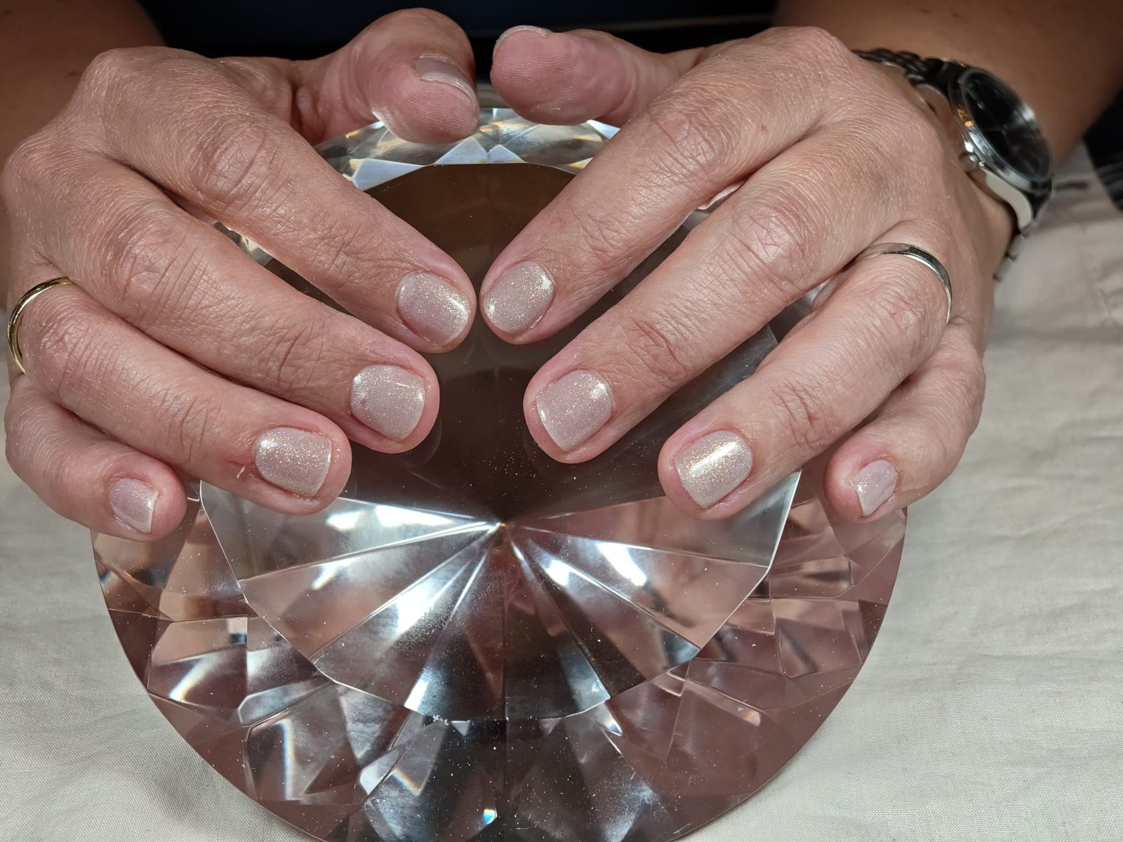 Natuurlijke parelmoer nagels, twee handen rond een geslepen kristal